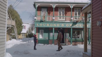 Movie still from “Snow Day” (2022), directed by Michael Lembeck – Two people standing outside of a grocery store in the snow; Wide shot, Over the shoulder angle