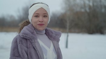 Movie still from “Snow Day” (2022), directed by Michael Lembeck – A woman in a purple coat and a white head band; Close Up shot, Over the shoulder angle