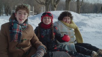 Movie still from “Snow Day” (2022), directed by Michael Lembeck – A group of people sitting in the snow together; Medium shot, Low angle