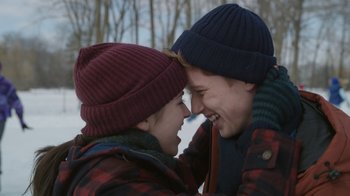 Movie still from “Snow Day” (2022), directed by Michael Lembeck – Two young people wearing winter hats are laughing; Medium shot, Over the shoulder angle