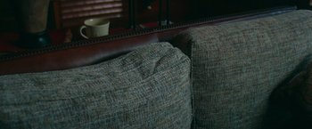Movie still from “Snow Falls” (2023), directed by Colton Tran – View of the back end of a couch; Extreme Close Up shot, High angle