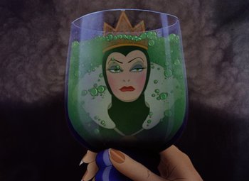 Movie still from “Snow White and the Seven Dwarfs” (1937), directed by Larry Morey – A hand is holding a wine glass with a picture of a woman; Close Up shot, Overhead angle