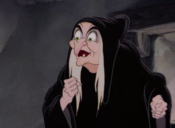 Movie still from “Snow White and the Seven Dwarfs” (1937), directed by Larry Morey – An old woman with long blonde hair wearing a black outfit; Close Up shot, Over the shoulder angle
