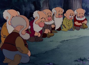 Movie still from “Snow White and the Seven Dwarfs” (1937), directed by Larry Morey – A group of dwarfs sitting in front of a tree; Medium shot, High angle