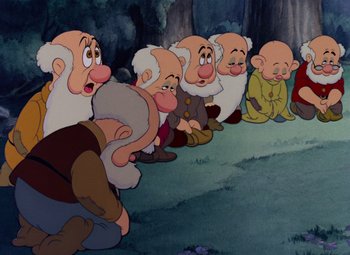 Movie still from “Snow White and the Seven Dwarfs” (1937), directed by Larry Morey – A group of dwarfs sitting on the ground in front of a tree; Medium shot, High angle