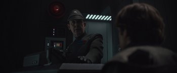 Movie still from “Solo: A Star Wars Story” (2018), directed by Ron Howard – A man in a uniform and a hat is holding a box; Close Up shot, Over the shoulder angle