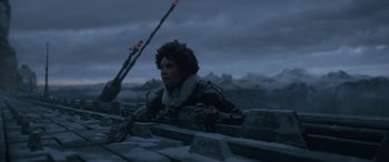 Movie still from “Solo: A Star Wars Story” (2018), directed by Ron Howard – A man sitting on a stone wall in the middle of the night; Medium shot, Low angle