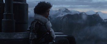 Movie still from “Solo: A Star Wars Story” (2018), directed by Ron Howard – A person sitting on top of a hill with a mountain in the background; Medium shot, Low angle