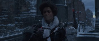 Movie still from “Solo: A Star Wars Story” (2018), directed by Ron Howard – A woman holding a cell phone while sitting on the ground; Close Up shot, Low angle