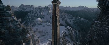 An aerial view of a clock tower in the middle of a snowy mountain range