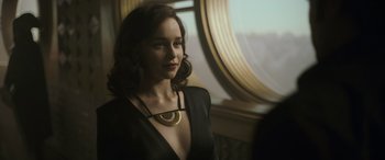 Movie still from “Solo: A Star Wars Story” (2018), directed by Ron Howard – A woman in a black dress with a gold necklace; Close Up shot, Over the shoulder angle
