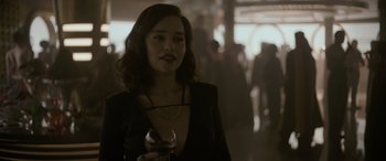 Movie still from “Solo: A Star Wars Story” (2018), directed by Ron Howard – A woman holding a glass of wine in a dark room; Close Up shot, Over the shoulder angle