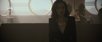 Movie still from “Solo: A Star Wars Story” (2018), directed by Ron Howard – A woman wearing a black dress and a gold necklace; Medium shot, Over the shoulder angle