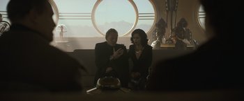 Movie still from “Solo: A Star Wars Story” (2018), directed by Ron Howard – A man and a woman looking at a cell phone in front of a round window; Medium shot, Over the shoulder angle
