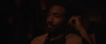 Movie still from “Solo: A Star Wars Story” (2018), directed by Ron Howard – A man with a beard wearing a neck tie; Close Up shot, Over the shoulder angle