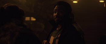 Movie still from “Solo: A Star Wars Story” (2018), directed by Ron Howard – A man in a black jacket is looking at the camera; Close Up shot, Over the shoulder angle