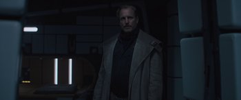 Movie still from “Solo: A Star Wars Story” (2018), directed by Ron Howard – A man standing in a dark room wearing a coat; Medium shot, Low angle