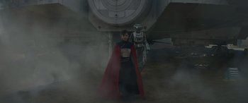 Movie still from “Solo: A Star Wars Story” (2018), directed by Ron Howard – A woman in a red cape standing next to a robot; Wide shot, Low angle