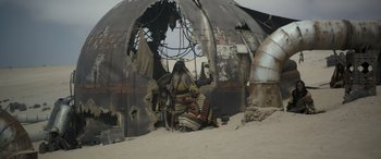 Movie still from “Solo: A Star Wars Story” (2018), directed by Ron Howard – A group of people sitting on top of a sandy beach; Wide shot, Low angle