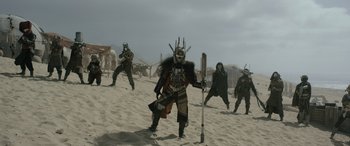 Movie still from “Solo: A Star Wars Story” (2018), directed by Ron Howard – A group of people standing on top of a sandy beach; Wide shot, Low angle