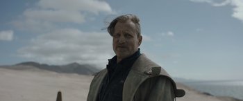 Movie still from “Solo: A Star Wars Story” (2018), directed by Ron Howard – A man with a beard is standing in the desert; Close Up shot, Over the shoulder angle