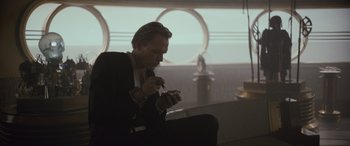 Movie still from “Solo: A Star Wars Story” (2018), directed by Ron Howard – A man in a suit and tie looking at a cell phone; Medium shot, Low angle