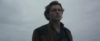 Movie still from “Solo: A Star Wars Story” (2018), directed by Ron Howard – A man in a brown and black jacket looking up at the sky; Close Up shot, Low angle