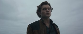 Movie still from “Solo: A Star Wars Story” (2018), directed by Ron Howard – A man in a brown and black jacket looking up at the sky; Close Up shot, Low angle