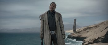 Movie still from “Solo: A Star Wars Story” (2018), directed by Ron Howard – A man standing on the beach holding a gun; Medium shot, Low angle