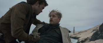 Movie still from “Solo: A Star Wars Story” (2018), directed by Ron Howard – A man is holding another man's hand while he is on the ground; Medium shot, Low angle