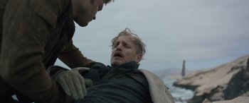 Movie still from “Solo: A Star Wars Story” (2018), directed by Ron Howard – A man being comforted by another man on the beach; Medium shot, High angle