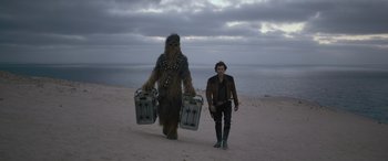 Movie still from “Solo: A Star Wars Story” (2018), directed by Ron Howard – A man standing next to a wookiee on the beach; Wide shot, Low angle