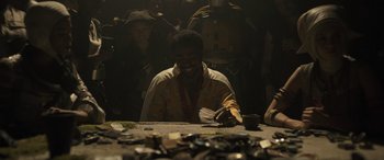 Movie still from “Solo: A Star Wars Story” (2018), directed by Ron Howard – A man sitting at a table with a bunch of papers; Medium shot, Over the shoulder angle