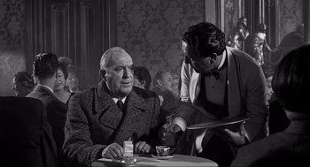 Movie still from “Some Like It Hot” (1959), directed by Billy Wilder – An older man sitting at a table in front of a waiter; Medium shot, Over the shoulder angle