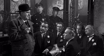 Movie still from “Some Like It Hot” (1959), directed by Billy Wilder – A black and white photo of a group of men sitting at a table; Medium shot, Over the shoulder angle