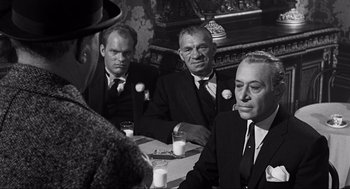 Movie still from “Some Like It Hot” (1959), directed by Billy Wilder – A group of men sitting at a table with drinks in front of them; Medium shot, Over the shoulder angle