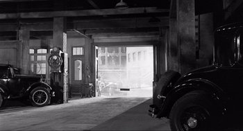 Movie still from “Some Like It Hot” (1959), directed by Billy Wilder – An antique car is parked in a garage; Extreme Wide shot, High angle