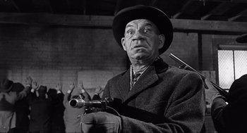 Movie still from “Some Like It Hot” (1959), directed by Billy Wilder – An old photo of an old man holding a gun; Medium shot, Low angle