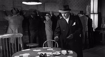 Movie still from “Some Like It Hot” (1959), directed by Billy Wilder – A group of people standing around a table; Medium shot, Over the shoulder angle