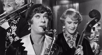 Movie still from “Some Like It Hot” (1959), directed by Billy Wilder – Two women are standing next to each other and one is playing a saxophone; Close Up shot, Over the shoulder angle
