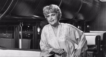 Movie still from “Some Like It Hot” (1959), directed by Billy Wilder – An old black - and - white photo of a woman holding a cane; Medium shot, Over the shoulder angle