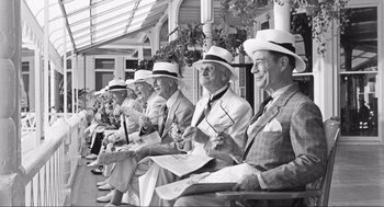Movie still from “Some Like It Hot” (1959), directed by Billy Wilder – A black and white photo of a group of men sitting on a bench; Wide shot, High angle