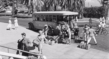 Movie still from “Some Like It Hot” (1959), directed by Billy Wilder – A group of people standing next to an old bus; Extreme Wide shot, High angle