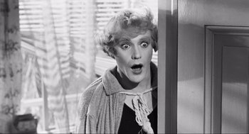 Movie still from “Some Like It Hot” (1959), directed by Billy Wilder – An old photo of a woman with a surprised look on her face; Close Up shot, Over the shoulder angle