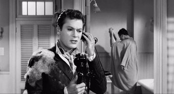 Movie still from “Some Like It Hot” (1959), directed by Billy Wilder – A man in a suit and tie holding a camera; Medium shot, Over the shoulder angle