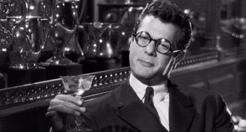 Movie still from “Some Like It Hot” (1959), directed by Billy Wilder – A black and white photo of a man holding a drink; Close Up shot, Over the shoulder angle