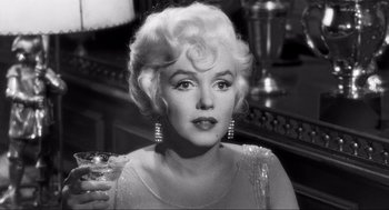 Movie still from “Some Like It Hot” (1959), directed by Billy Wilder – A woman in a white dress holding a glass; Close Up shot, Over the shoulder angle