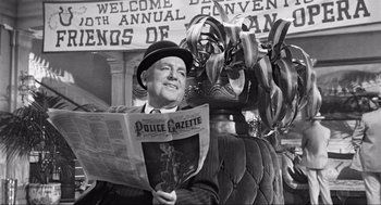 Movie still from “Some Like It Hot” (1959), directed by Billy Wilder – A black and white photo of a man reading a newspaper; Medium shot, High angle