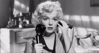 Movie still from “Some Like It Hot” (1959), directed by Billy Wilder – A woman holding a hair dryer and a hair brush; Close Up shot, High angle