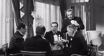 Movie still from “Some Like It Hot” (1959), directed by Billy Wilder – A black and white photo of a group of men sitting around a table; Medium shot, Over the shoulder angle